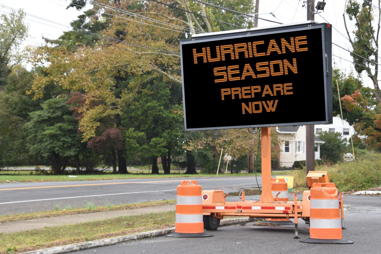 Digital electronic mobile road sign that says Hurricane Season prepare now, on the side of a tree lined neighborhood road; Shutterstock ID 1434993110