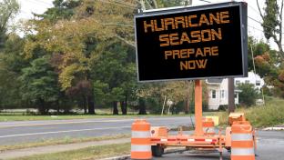 Digital electronic mobile road sign that says Hurricane Season prepare now, on the side of a tree lined neighborhood road; Shutterstock ID 1434993110