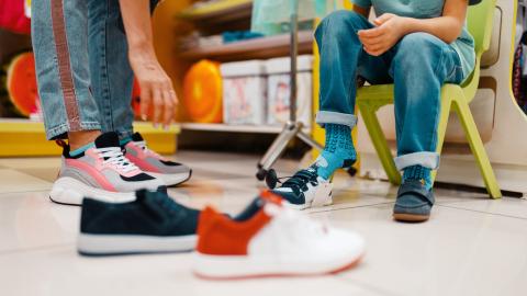 Mother with children choosing shoes in kids store; Shutterstock ID 1498054124