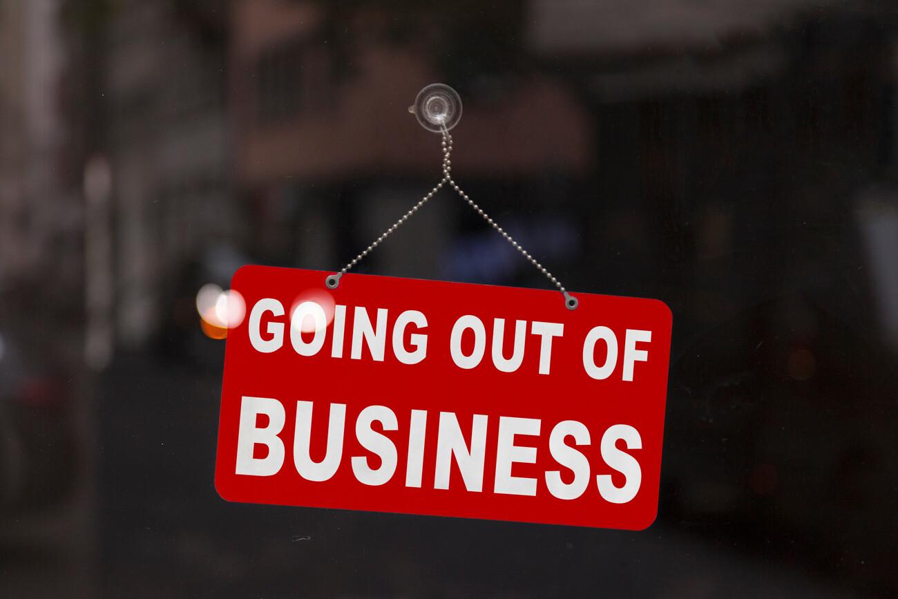 Close-up on a red closed sign in the window of a shop displaying the message "Going out of business".; Shutterstock ID 1721205958