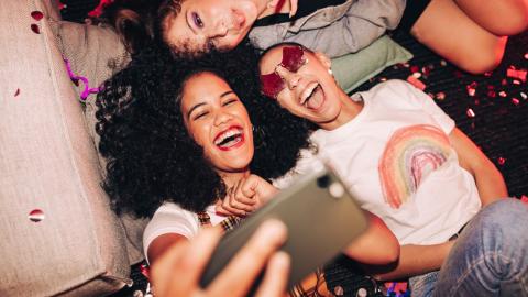 Vibrant selfies for vibrant people. Overhead view of three happy friends taking a selfie while lying on the floor at a house party. Group of cheerful female friends having fun together on the weekend.; Shutterstock ID 2135759921